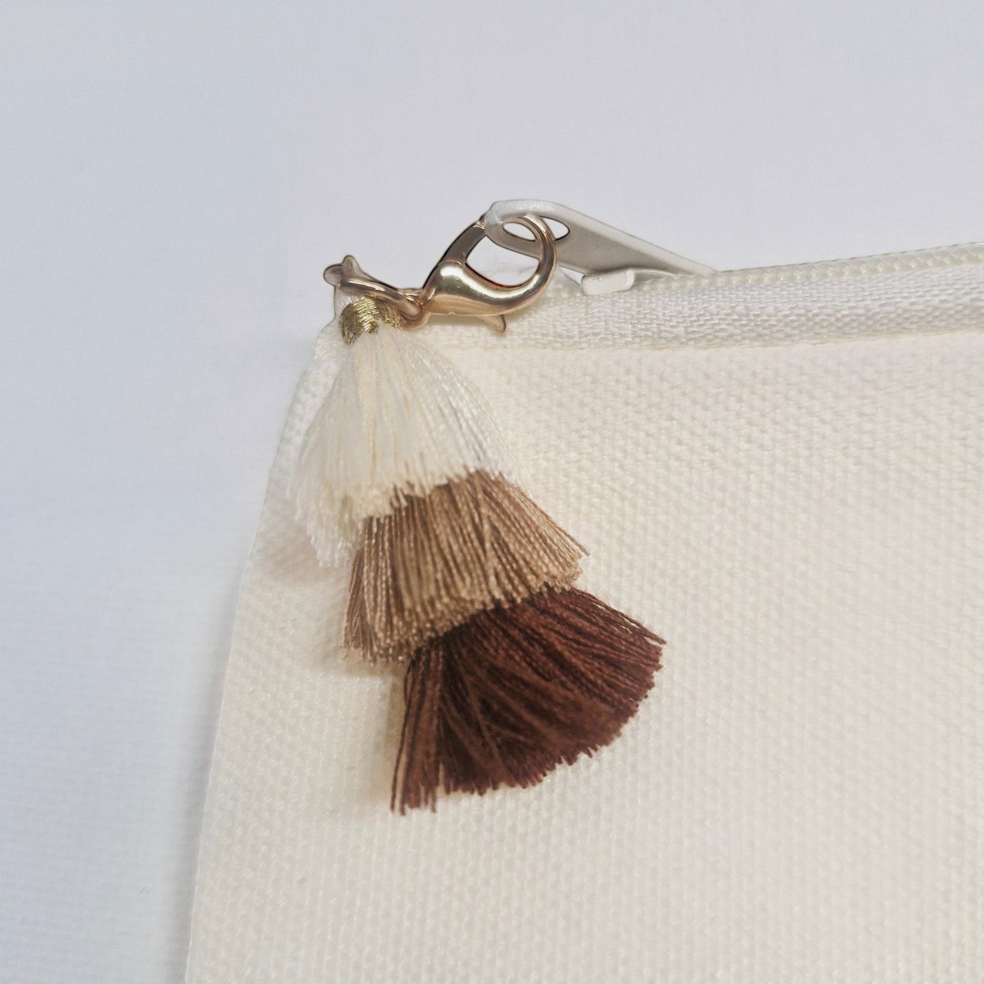 Pochette en lin écru Femmes de pilotes avec pompons dégradés marron et fermoir doré.