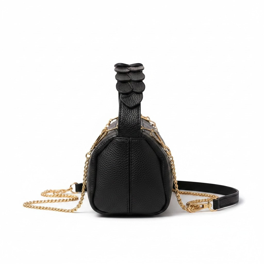 Femmes de pilotes Sac Pétale noir en cuir grainé, anse sculptée façon pétales, bijouterie dorée, bandoulière chaîne.